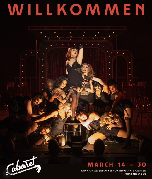 Cabaret production photo: the Kit Kat Club company posed around a stool on a red-lit stage under the word Willkommen