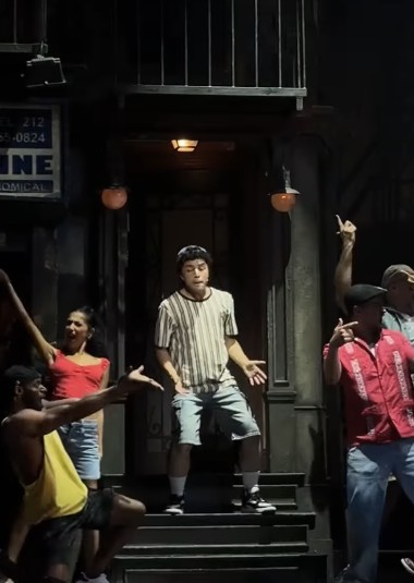In the Heights reel: the lead mid-number on a brownstone stoop, the company dancing around him